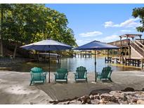 Private beach with lounge chairs, umbrellas, and lake access on a sunny day at 18420 Rosapenny Rd, Charlotte, NC 28278