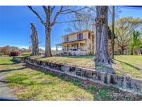 Two story home with a charming porch, mature trees, and red shutters at 2114 Whitworth Rd, Cherryville, NC 28021