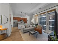 Bright living room featuring an open floor plan, hardwood floors, and a balcony with city views at 230 S Tryon St # 610, Charlotte, NC 28202