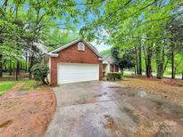 Traditional brick and vinyl home with a two-car garage and mature trees at 6520 White Pine Ln, Charlotte, NC 28262