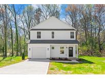 Charming two-story home boasts a symmetrical facade, attached garage, and freshly laid driveway on a verdant lawn at 701 Applewood St, Kannapolis, NC 28081