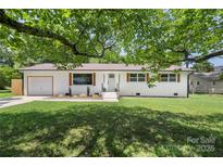 Charming home with green lawn, brick facade, matching shutters, and a lovely shade tree in a desirable neighborhood at 1315 Vickie Ln, Matthews, NC 28104