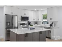Modern kitchen featuring white cabinets, stainless steel appliances, and a large island with a white countertop at 1315 Vickie Ln, Matthews, NC 28104