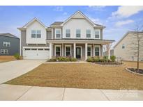 Inviting two-story home features a covered front porch, attached garage, and well-maintained lawn at 19412 Bird Meadow Dr, Huntersville, NC 28078