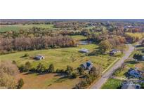 Expansive aerial view of a beautiful multi-acre property featuring a house and multiple outbuildings, plus a pond and wooded area at 3526 Harmony Hwy, Harmony, NC 28634