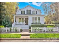Charming two-story home featuring a cozy front porch, white picket fence and mature landscaping at 411 Walnut St, Davidson, NC 28036