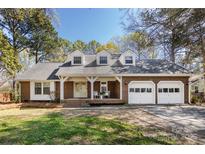 Charming brick home featuring a three-car garage, dormer windows, and a cozy front porch at 5013 Cedar Forest Dr, Charlotte, NC 28226
