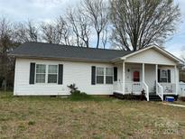 Charming single-story home featuring vinyl siding, a covered porch, and manicured landscaping at 300 S Oakland Ave, Statesville, NC 28677