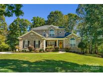 Beautiful brick home with manicured lawn, mature trees, and welcoming yellow front door at 4586 Chanel Ct, Concord, NC 28025