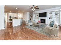 Bright living room featuring a fireplace, built-in shelving, and a ceiling fan at 7854 Springs Village Ln, Charlotte, NC 28226