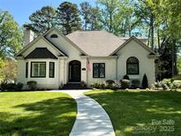 Charming white brick home features manicured lawn, a welcoming walkway and lush landscaping at 105 Beach Ln, Mooresville, NC 28117