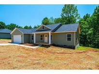 Charming single-story home with a covered front porch and an attached garage, nestled among mature trees at 1127 Mckay Rd, Newton, NC 28658