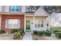 Charming townhome featuring a brick facade, green door, and well-maintained landscaping at 11630 Retriever Way, Charlotte, NC 28269