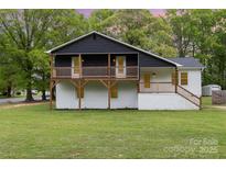 Renovated two-story home with a black upper level, white brick foundation, and inviting second story wood balcony at 5316 Teakwood Dr, Kannapolis, NC 28083