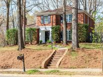 Traditional red brick two-story home with manicured landscaping, brick staircase and shuttered windows at 9101 Sardis Forest Dr, Charlotte, NC 28270