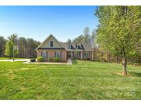 Inviting brick home with a well-manicured lawn, mature trees, and a basketball court in the driveway at 16 Shadow Dr, Taylorsville, NC 28681