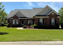 Charming brick home with lush green lawn and well-manicured landscaping at 6144 Abergele Ln, Matthews, NC 28104