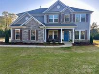 Charming two-story home with stone accents, neat landscaping, and a welcoming blue front door at 8011 Caliterra Dr, Charlotte, NC 28227