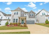 Charming two-story home featuring stone accents, a gray garage door, and manicured landscaping at 11036 Shreveport Dr, Huntersville, NC 28078