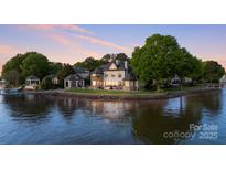 Stunning waterfront home with stone accents, lush landscaping, and serene water views at sunset at 114 Ventana Ct, Mooresville, NC 28117