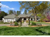 Beautiful front exterior of home with lush lawn, a vine covered pergola, seating, and mature trees at 2015 Pellyn Wood Dr, Charlotte, NC 28226
