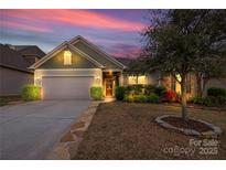 Charming single-story home featuring manicured landscaping, a two-car garage, and a welcoming entrance at dusk at 2035 Palace Way, Indian Land, SC 29707