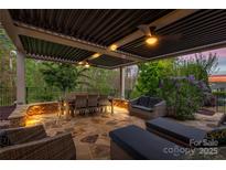 This outdoor patio features stone floors, ample seating, and an overhead pergola for comfortable outdoor living at 2035 Palace Way, Indian Land, SC 29707