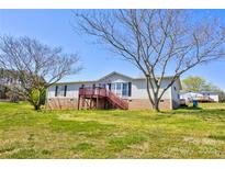 View of home exterior with lawn, mature trees, deck, and blue sky background at 216 Sylvan Rd, China Grove, NC 28023