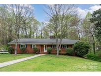 Charming one-story brick home with a well-manicured front lawn and mature trees at 2714 Dogwood Cir, Charlotte, NC 28208