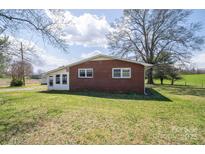 Brick exterior with a well-maintained lawn and an attached sunroom, offering a serene outdoor view at 396 Tower Rd, Vale, NC 28168