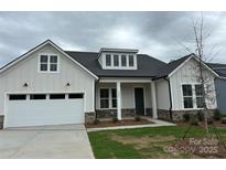 Charming home featuring a light gray exterior, a two-car garage and a welcoming front porch at 5205 Mint Harbor Way # 0353, Charlotte, NC 28269