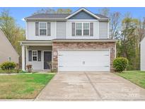 Inviting home features a 2-car garage, stone details, neutral siding and a neatly manicured lawn at 9230 Avery Meadows Dr, Charlotte, NC 28216