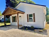 Charming home featuring white siding, a covered porch, and well-maintained landscaping at 1067 Old Charlotte Rd, Concord, NC 28027