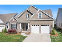 Charming home with a two-car garage, stone accents, and manicured lawn at 14015 Cameryn Elise Dr, Cornelius, NC 28031