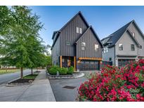 Stunning modern home featuring dark siding, a pergola over the garage, and beautiful landscaping at 1505 Landis Ave, Charlotte, NC 28205