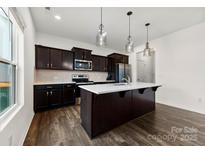 Modern kitchen features dark wood cabinets, stainless steel appliances, and an island with white countertop at 1976 Ethan Ln, Stanfield, NC 28163