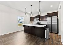 This kitchen features an island, stainless steel refrigerator, hardwood floors, and modern pendant lighting at 1976 Ethan Ln, Stanfield, NC 28163
