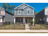 Charming two-story home featuring a stone facade, inviting front porch, fenced front yard, and meticulous landscaping at 504 Cranford Dr, Pineville, NC 28134