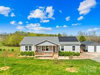 Charming single story home featuring solar panels, a welcoming front porch, and well-manicured landscaping at 909 Old Mocksville Rd, Statesville, NC 28625