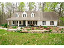 Charming home featuring a well-manicured lawn, a welcoming front porch with rocking chairs, and beautiful landscaping at 9820 Janeiro Dr, Huntersville, NC 28078