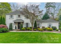 Charming two-story home with white brick, green shutters, mature trees, and a lush, landscaped front yard at 1529 S Wendover Rd, Charlotte, NC 28211
