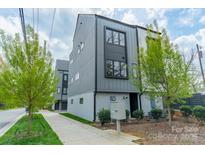 Modern townhome showcasing gray siding, large windows, manicured landscaping, and a well-kept sidewalk at 1933 W Trade St, Charlotte, NC 28216