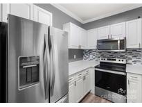 Updated kitchen featuring stainless steel appliances, white cabinets, and mosaic backsplash at 6359 Mallard View Ln, Charlotte, NC 28269