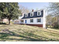 Charming home with a manicured lawn, dormer windows, and a blue door at 916 Rollingwood Dr, Mount Holly, NC 28120