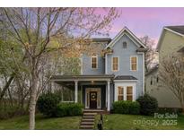 Charming two-story home features a welcoming porch, a well-manicured lawn, and beautiful landscaping at 9832 Sunriver Rd, Huntersville, NC 28078