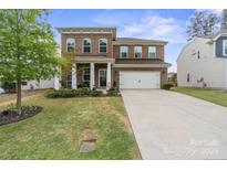 Charming brick two-story home featuring a manicured lawn and a spacious two-car garage at 121 Little Kennerly Dr, Mooresville, NC 28115