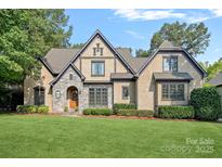 Charming Tudor-style home with manicured lawn, stone accents and mature landscaping at 1407 Becklow Ct, Wesley Chapel, NC 28079