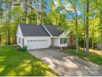 Charming single-story home with an attached two-car garage, lush lawn, and mature trees on a sunny day at 1628 Rosegate Ln, Stanfield, NC 28163