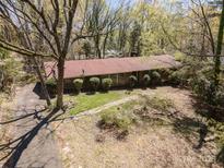 Expansive aerial view of a single-story home featuring a classic red roof and surrounded by lush greenery and mature trees at 340 Sardis N Rd, Charlotte, NC 28270