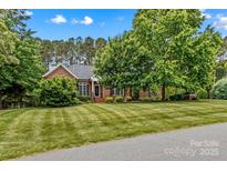 Charming brick home featuring a lush, manicured front lawn and mature trees offering great curb appeal at 4159 Isle Of Pines Dr, Denver, NC 28037